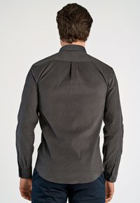 Donkergrijze overhemd met lange mouwen, een puntkraag en subtiele textuur. Bevat een achterlending en een gebogen zoomontwerp.