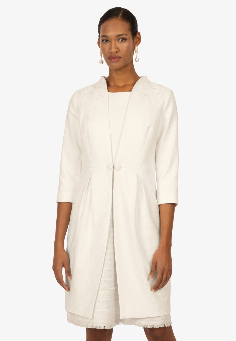 White floral textured coat with a shawl collar, three-quarter sleeves, and a single button closure, paired with a white dress beneath.
