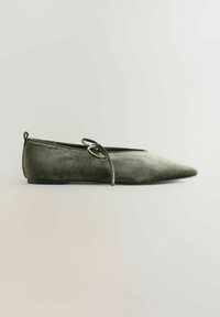 Spidse flade sko i olivenfarvet velour med dekorative snørebånd og minimal sort sål. Glat tekstur med et strømlinet design.