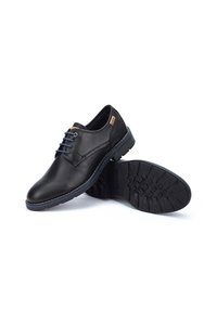 Chaussures habillées en cuir noir avec des lacets bleus, semelle en caoutchouc, bout rond, couture contrastante et petite étiquette de marque sur le côté.