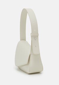 Sac à épaule en cuir couleur crème avec une forme triangulaire structurée et une bandoulière réglable avec coutures visibles et petite fermeture métallique.