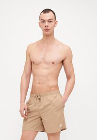 Beige úszóshort, elasztikus derékkal, zsinóros részletekkel és oldzsebekkel, könnyű anyagból készült, vízi tevékenységekhez ideális.