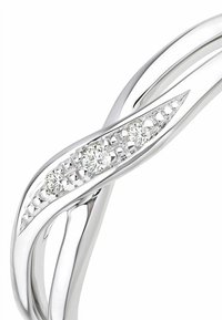 Sidabrinės spalvos užsukta apyrankė su tekstūruotu paviršiumi, kurios centre yra suformuota eilė apvalių skaidrių kristalų, įrėmintų elegantiškame kanalo dizaino pagrinde.