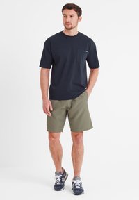 Navy cotton T-shirt with a chest pocket, paired with olive green shorts. Worn with navy sneakers featuring white laces and gray accents.