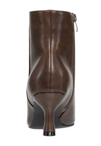 Botín de piel marrón con tacón fino estilo kitten y cremallera trasera, visto desde atrás.