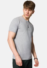 Szary bawełnowy t-shirt z krótkim rękawem, okrągłym dekoltem i dopasowanym krojem. Posiada gładką fakturę i minimalną ilość szwów, co podkreśla casualowy wygląd.