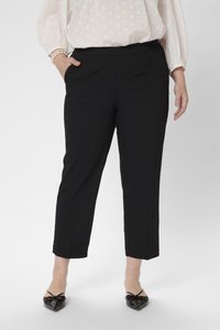 Schwarze knöchellange Hosen mit glatter Textur, ausgestattet mit Seitentaschen und einem flachen Bund. Kombiniert mit schwarzen spitzen Ballerinas.