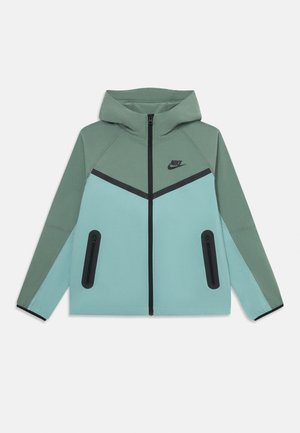 Nike-Hoodie mit zweifarbigen grünen und hellblauen Paneelen, schwarzem Reißverschluss, Reißverschlusstaschen und Nike-Logo auf der Brust, flach ausgelegt auf weißem Hintergrund.