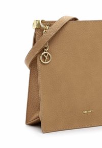 Borsa a mano in pelle color testa di moro con finitura testurizzata, hardware dorato e tracolla removibile. Presenta un ciondolo circolare e dettagli con il marchio.