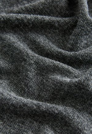 Grått stickat tyg med en texturerad yta, som har en mjuk och något fluffig uppsyn. Materialet visar subtila variationer i nyans.