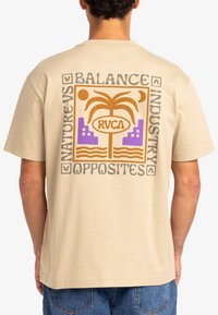 Beige t-shirt featuring a graphic design on the back with a palm tree, geometric shapes, and text in orange, purple, and gray tones.