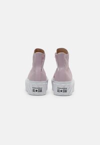 Rosa kanvas högskor med en slät yta, vit gummisula och logodetaljer på hälen, med en dragkedja baktill.