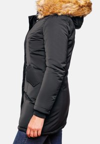 Černý prošívaný kabát s lehkým hnědým umělým kožichem na kapuci, bočními kapsami, žebrovanými manžetami a délkou po kolena. Hladká textura a teplý materiál.