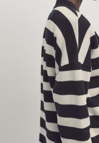 Sweter dzianinowy z wyraźnymi poziomymi paskami w kolorze granatowym i kremowym, z dekoltem typu crew neck oraz luźnym fasonem i charakterystyczną teksturą ściegów.