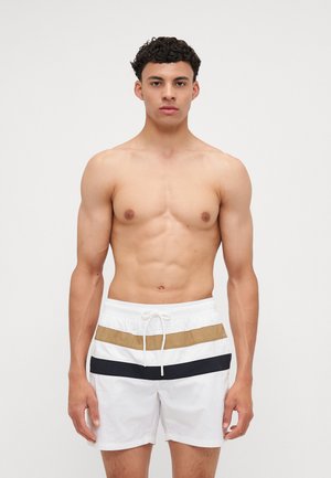 Shorts de bain blancs avec des rayures horizontales beiges et bleu marine. Dotés d'une taille élastique avec cordon de serrage. Texture de tissu lisse.