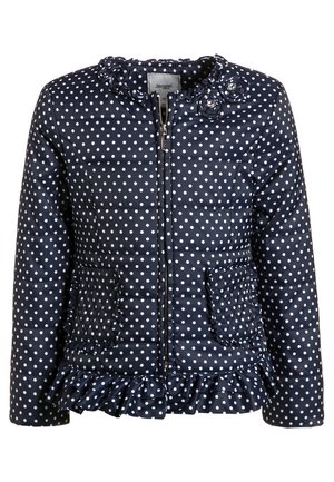 Veste matelassée bleu marine à pois blancs, col et ourlet volantés, fermeture éclair devant, deux poches volantées et appliques florales décoratives près du cou.