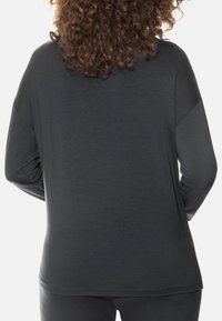 Donkere grijs lange mouwen shirt met een ontspannen pasvorm, met een zachte textuur en een gebogen zoom aan de onderkant, getoond vanuit de achterkant.