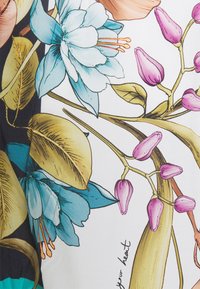 Blomsterprintdesign på stof med blå blomster, lyserøde knopper og grønne blade. Baggrunden er hvid med et kontrasterende mørkt element.