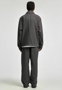 Szara i czarna, oversize'owa kurtka w paski oraz pasujące do niej spodnie, wykonane z teksturowanej tkaniny, z klasycznym kołnierzem i luźnym krojem.