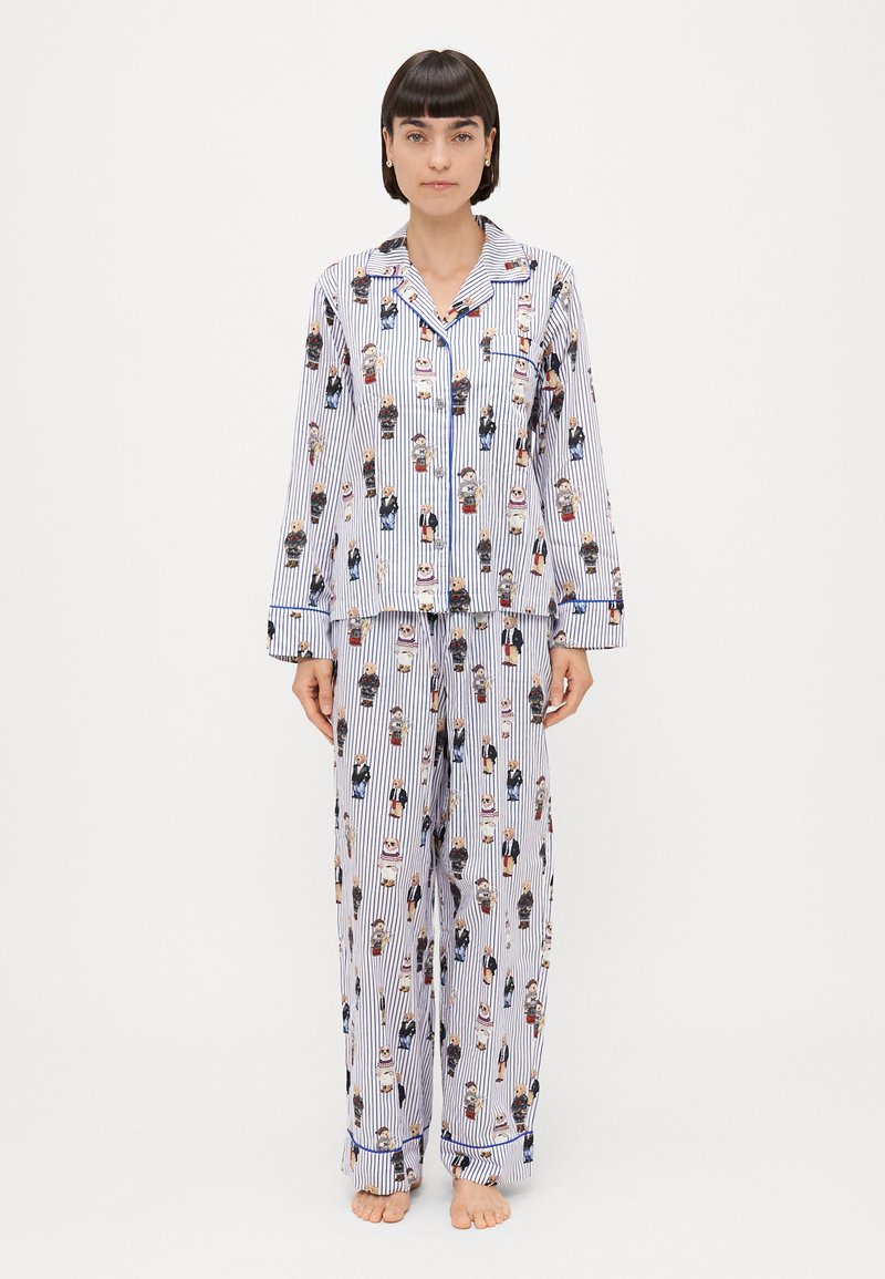 Conjunto de pijama listrado azul e branco com personagens de desenhos animados, mangas longas e calças largas com um top abotoado e bolso.