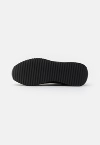 Black shoe sole featuring a textured, ridged pattern for traction. The bottom has a smooth edge and a robust, durable design.