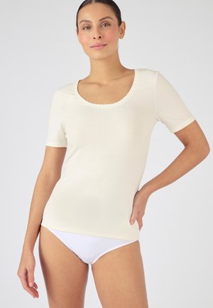 Crèmekleurig top met korte mouwen en een geschulpte halslijn, gemaakt van zachte materialen; gecombineerd met witte onderkleding. Soepele textuur, eenvoudig ontwerp.