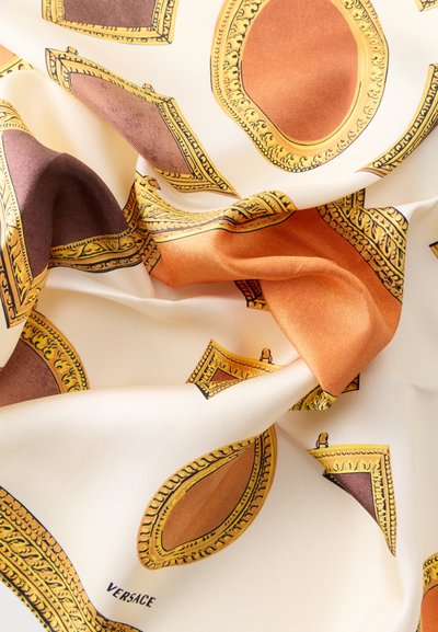 Ύφασμα από μετάξι με καστανά και πορτοκαλί διακοσμητικά οβάλ και ορθογώνια πλαίσια σε κρεμ φόντο, με το λογότυπο «Versace» στη γωνία.