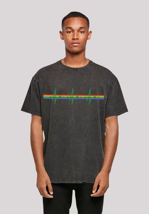 Black oversized t-shirt in soft cotton with a crew neck, featuring a multicolored heartbeat graphic and short sleeves.