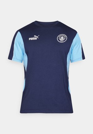 Tamsiai mėlynas ir šviesiai mėlynas medvilninis trumpomis rankovėmis marškinėliai su apvaliu iškirpimu, Puma logotipu ir Mančesterio miesto emblema ant krūtinės.