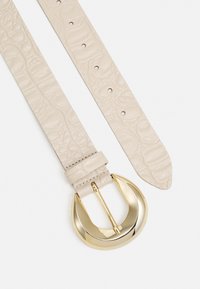 Ceinture en cuir synthétique beige avec un motif crocodile texturé, dotée d'une grande boucle en métal doré et de cinq trous d'ajustement.