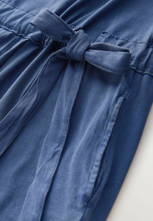 Denimkjole i blødt blåt stof med bindebånd i taljen, vandrette sømme og to sidelommer. Glat tekstur, afslappet pasform.