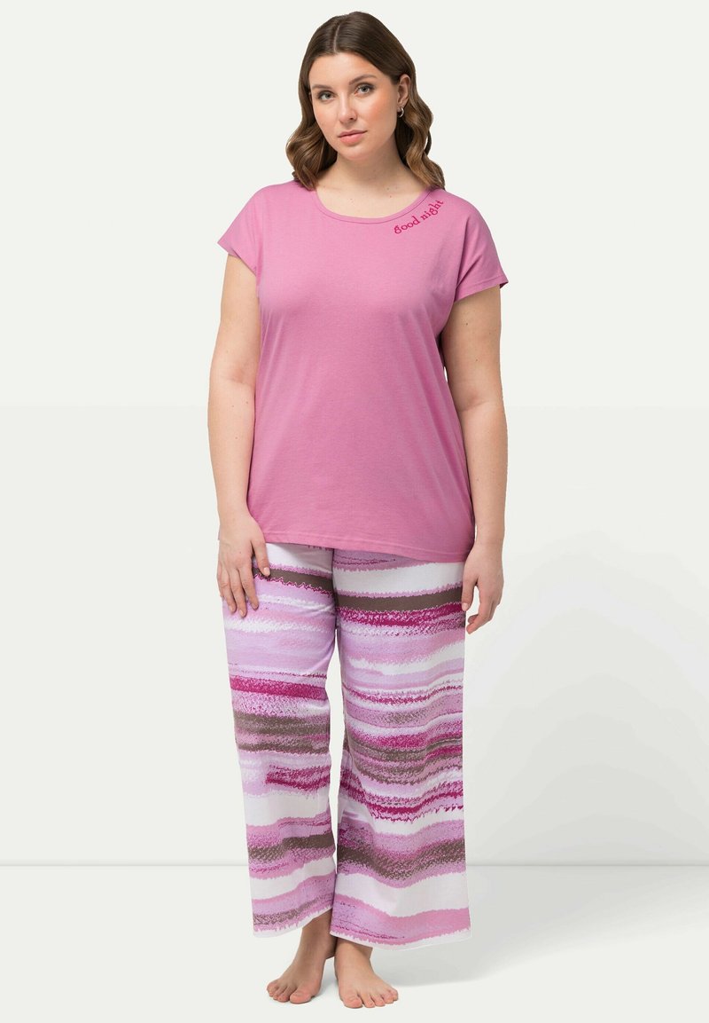 Rosa kortärmad T-shirt med broderi av "good night", kombinerad med vida byxor med horisontella ränder i rosa, vitt och brunt.