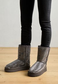 Grå glitrende ankelstøvler med en myk tekstur, dekket av rhinestones, med flatt såle og rund tå.