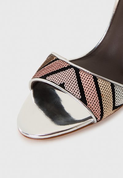 Σανδάλι με ψηλό τακούνι και μεταλλικό ασημί δακτύλιο, διαθέτον�τας πολύχρωμη ακολουθία παγιέτας σε μαύρα, ροζ και χρυσά γεωμετρικά σχέδια.