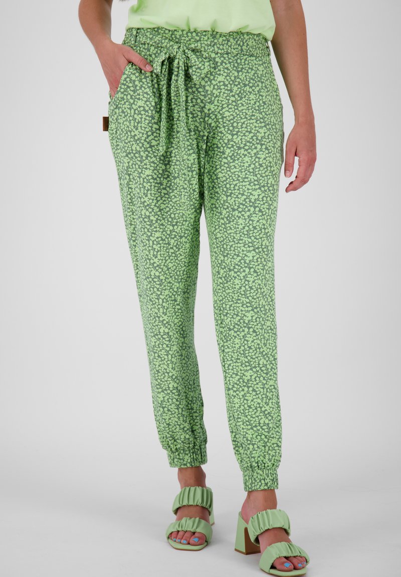 Pantalones verdes con un pequeño patrón floral, cinturilla elástica, bolsillos laterales, puños fruncidos y un corte relajado. Combinados con sandalias de tacón verde menta.