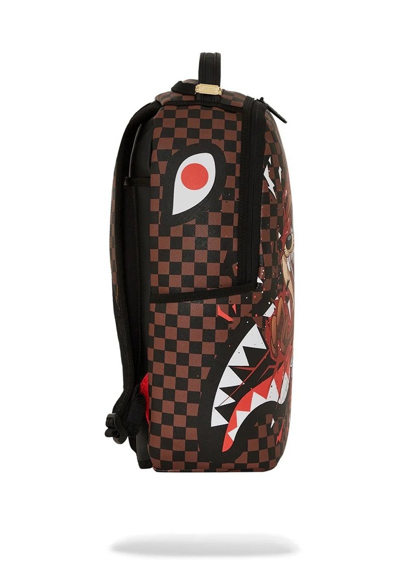 Una mochila a cuadros en negro y marrón que presenta un estampado gráfico de una cara feroz con dientes afilados y acentos rojos. Incluye compartimentos con cremallera.