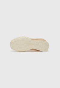 Botte de sport légère avec un dessus en pêche texturé et une semelle extérieure crème durable dotée d'une semelle à motifs pour une meilleure adhérence.