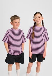 Lila gestreifte T-Shirts mit schwarzen Streifen, kurzen Ärmeln und kleinem Logo. Getragen mit schwarzen Shorts und weißen Socken, nebeneinander stehend.