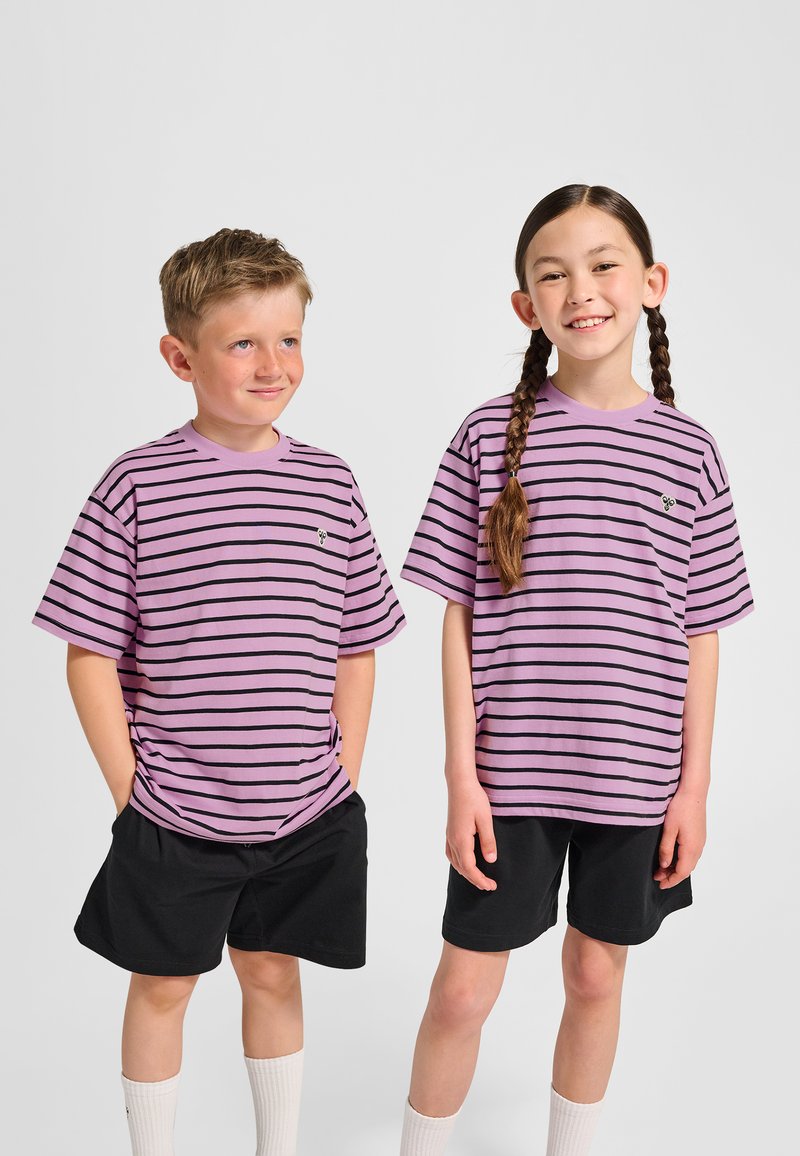 Lila gestreifte T-Shirts mit schwarzen Streifen, kurzen Ärmeln und kleinem Logo. Getragen mit schwarzen Shorts und weißen Socken, nebeneinander stehend.