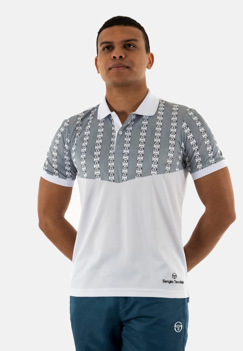 Polo con parte superiore grigia a fantasia con loghi ripetuti, parte inferiore bianca uniforme e colletto classico. Abbinato a pantaloni corti blu scuro.