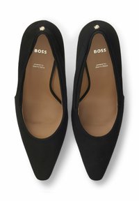 Scarpe nere con punta appuntita e texture morbida. All'interno presentano suole marroni e marchio. Dettaglio hardware notevole, un piccolo accento dorato sulla punta.