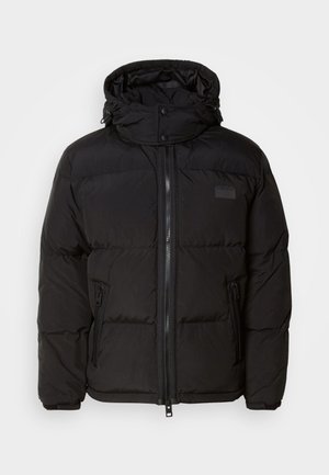 Casaco acolchoado preto com capuz, fecho éclair e bolsos laterais. Apresenta um design acolchoado, textura suave e um patch de logótipo no peito.