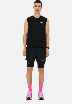 Tee-shirt sans manches noir et shorts, rehaussés du logo "cep" blanc. Chaussettes et chaussures rose néon présentent un design dégradé.