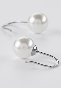 Hvite perle-dråpe øredobber med en glatt overflate, metalliske sølvkroker og en rund form. Enkelt og elegant design.