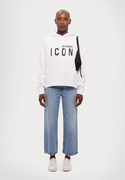 White hoodie with "ICON" text in black, paired with light wash, wide-leg jeans and white sneakers. Simple design and casual fit.