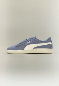 Μπλε σουέντ αθλητικό παπούτσι Puma με λευκή ρίγα και σόλα, σχεδιασμός με κορδόνια και λογότυπο Puma στο πλάι και στη σόλα, σε ουδέτερο φόντο.