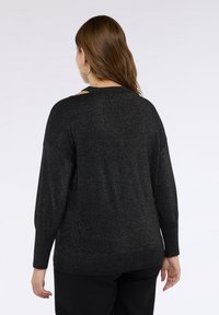 Czarny sweter o metalicznym połysku, z długimi rękawami i luźnym krojem. Posiada wycięcia przy dekolcie oraz prążkowany dół.