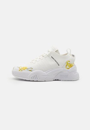 Baskets blanches Versace Jeans Couture avec semelle épaisse, dessus en maille, languette et accents jaune baroque sur l'avant-pied et le talon.