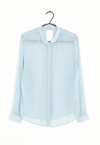 Blusa trasparente blu chiaro con sottili righe verticali bianche, colletto e chiusura frontale con bottoni. Maniche lunghe con dettagli ai polsini.