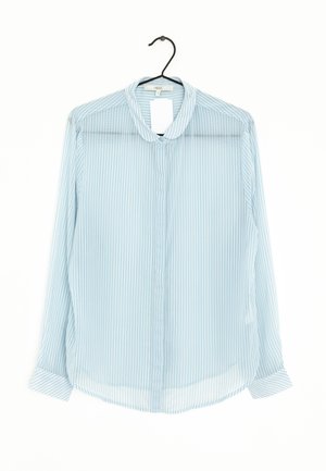 Jasnoniebieska przezroczysta bluzka z cienkimi białymi pionowymi paskami, kołnierzykiem i zapięciem na guziki z przodu. Długie rękawy z detalami przy mankietach.